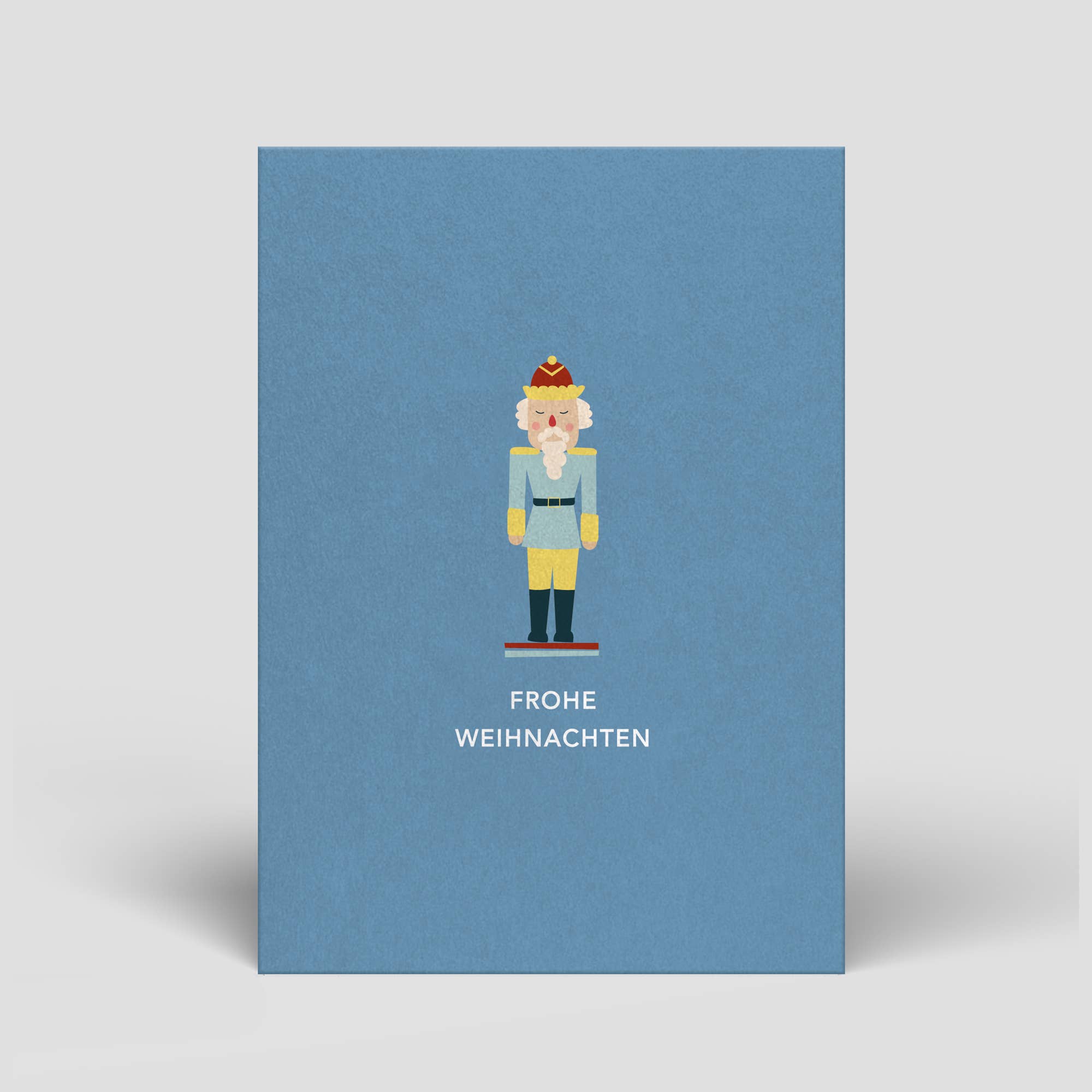 Postkarte „Frohe Weihnachten“ – Nussknacker auf blauem Hintergrund