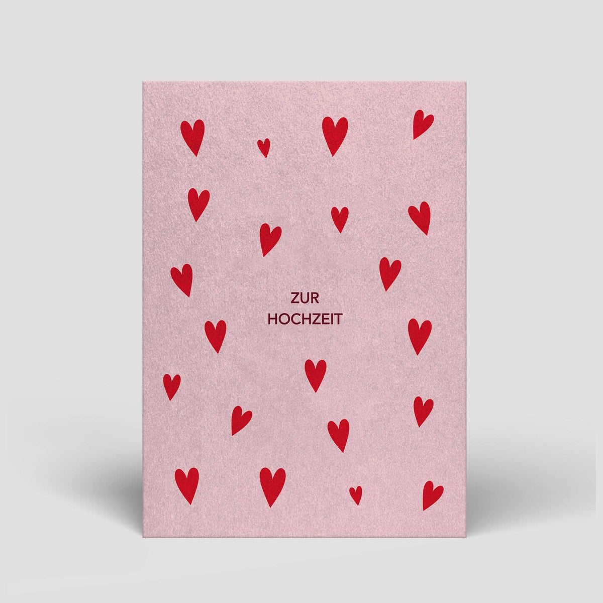 Hochzeitskarte „Zur Hochzeit“ mit roten Herzen auf zartrosa Grund von Naturbedacht, Vorderseite